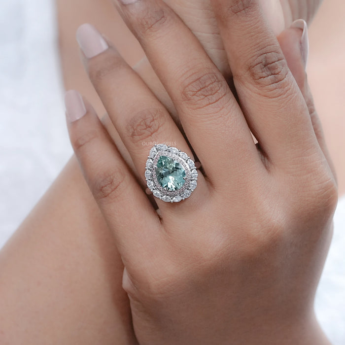 pear gemstone double halo aquamarine engagement ring on model's finger