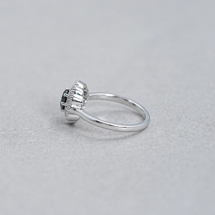 side view of round black diamond double halo engagement ring on grey fabric