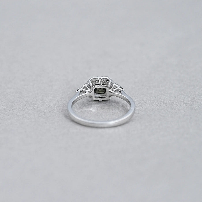 back view of asscher cut black diamond halo engagement ring on grey background