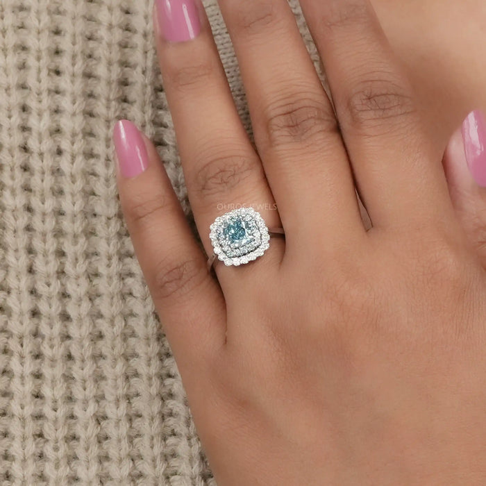 fancy blue cushion cut diamond double halo engagement ring on model's finger
