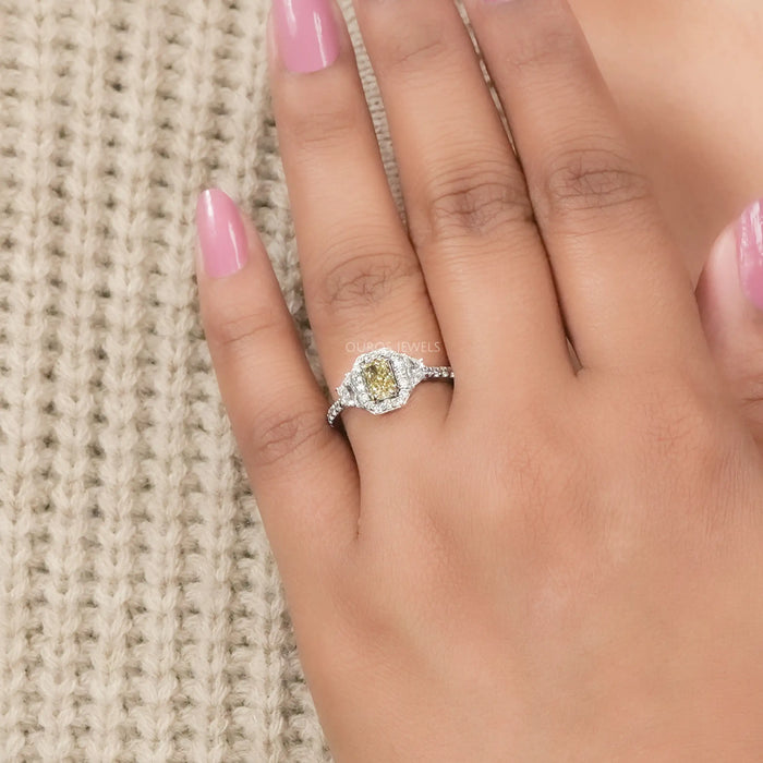 yellow radiant cut diamond three stone halo engagement ring on model's finger