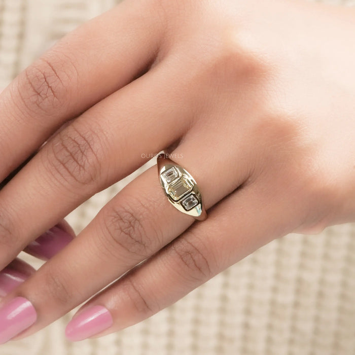 yellow emerald-cut diamond 3 stone bezel set colored engagement ring in finger