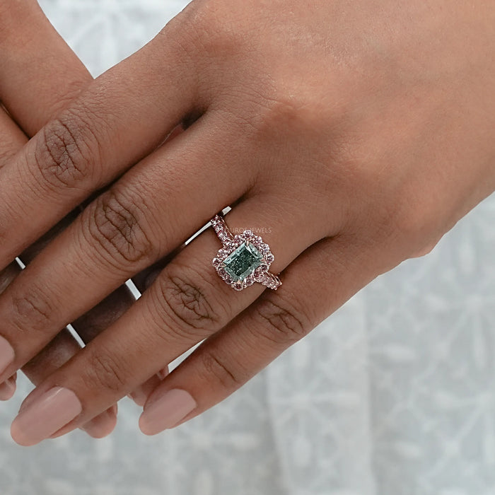 green radiant cut diamond with pink diamond halo engagement ring in finger