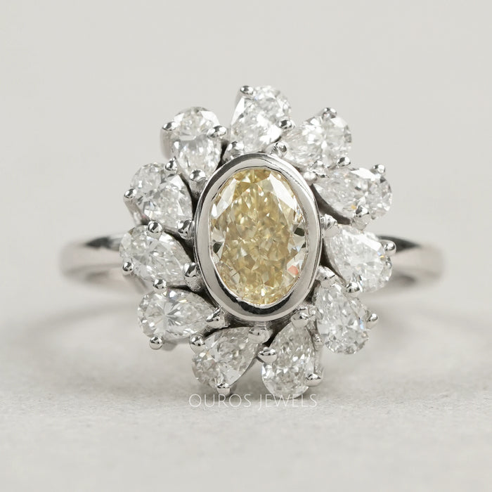 top view of yellow oval cut diamond bezel set with pear halo engagement ring