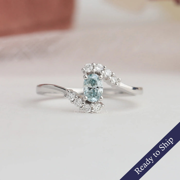 Front view of green oval shaped diamond set in bypass, this engagement ring made of 14k white gold & side round cut small side diamonds.
