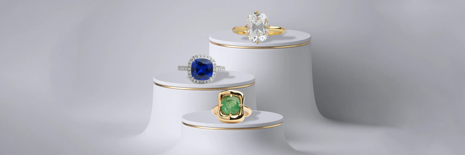 Image showing Cushion sapphire halo ring alongside a cushion solitaire engagement ring and a cushion emerald bezel-set ring