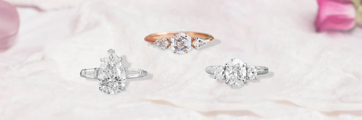 Three stone lab-grown diamond engagement rings displayed on white pedestals – radiant, oval yellow, and emerald cut in gold settings