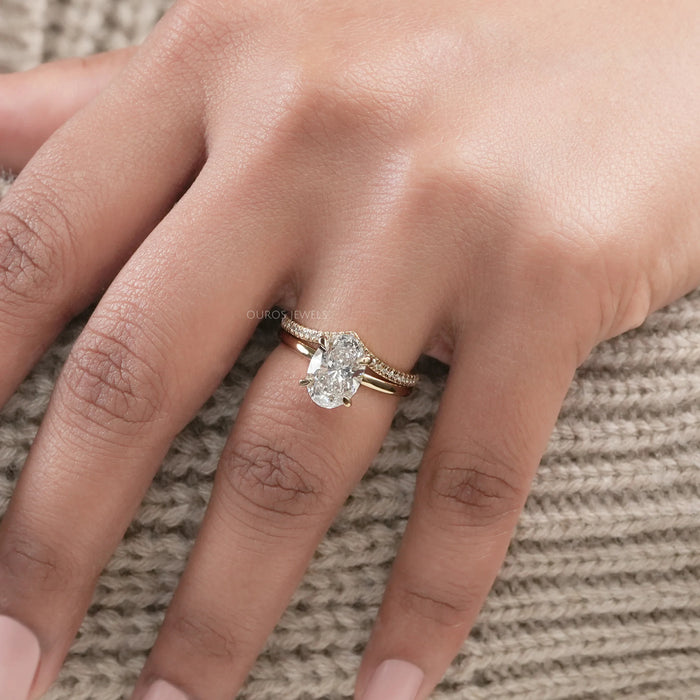 oval-cut lab diamond curved bridal ring set with yellow gold band in finger