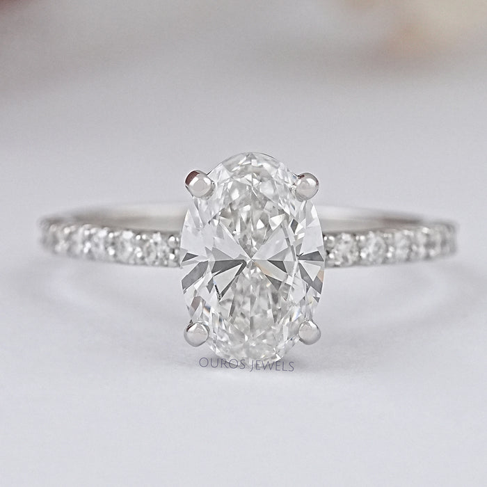 front view of oval-shaped diamond solitaire accent engagement ring on grey fabric