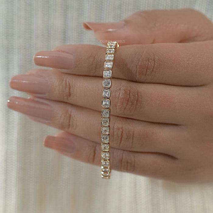 asscher cut ethically grown diamonds bezel set tennis bracelet in yellow gold on hand