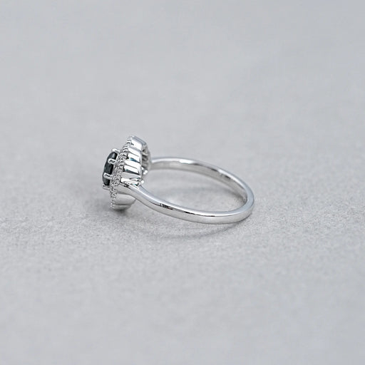 side view of round black diamond double halo engagement ring on grey fabric