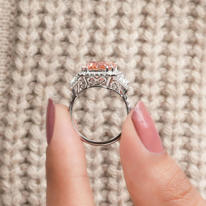 close view of pink emerald cut diamond three stone halo engagement ring