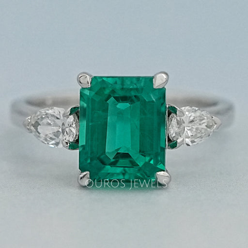 front view of green emerald gemstone pear diamond three stone engagement ring