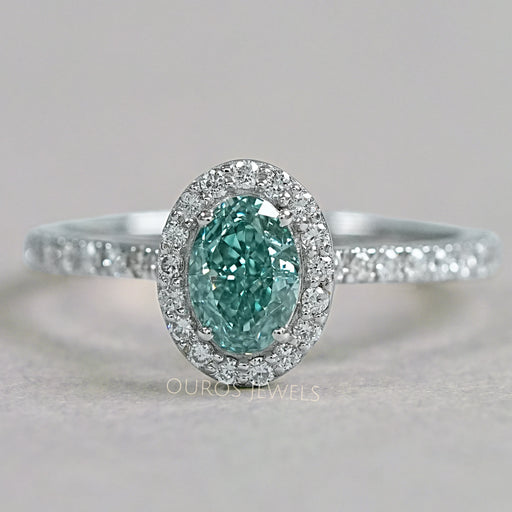 top view of fancy vivid green oval cut diamond halo wedding ring on grey fabric