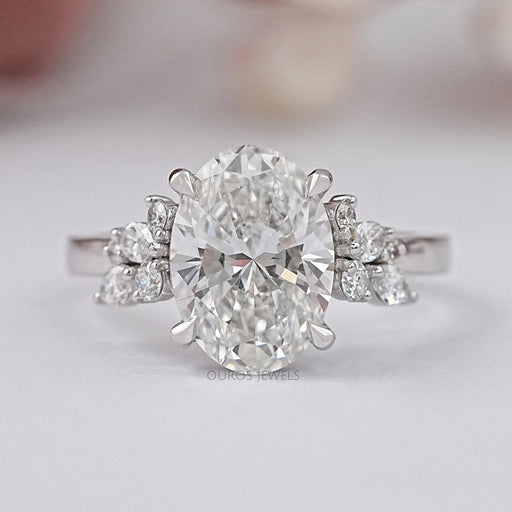 front view of oval-cut lab diamond cluster solitaire engagement ring on grey fabric