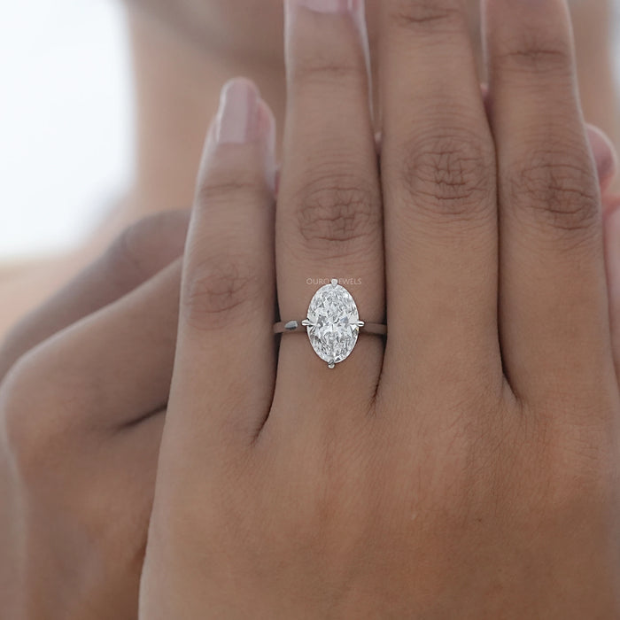 front view of 3 carat oval cut diamond hidden halo engagement ring in finger