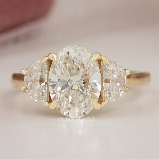 front view of oval cut diamond three stone engagement ring with yellow gold band