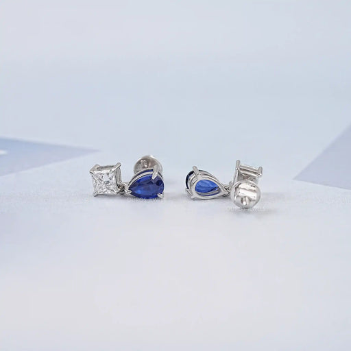 top and back view of pear sapphire and princess diamond two tone drop earrings