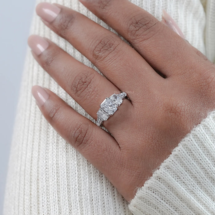 radiant cut diamond five stone engagement ring with white gold band on model's finger