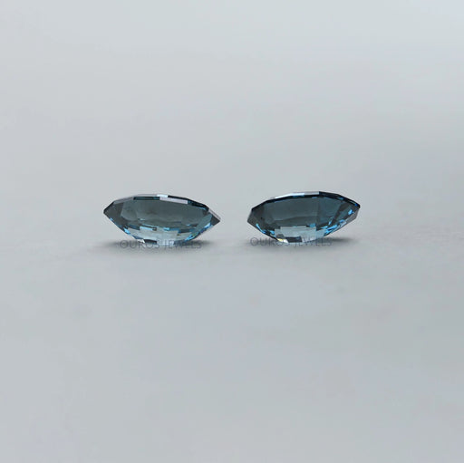 side view of step cut blue oval shaped lab created diamonds pair