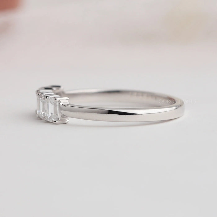 side view of emerald cut lab diamond five stone wedding band on grey fabric