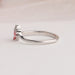 Side view of princess cut pink diamond ring made of curved band in 14k white gold.
